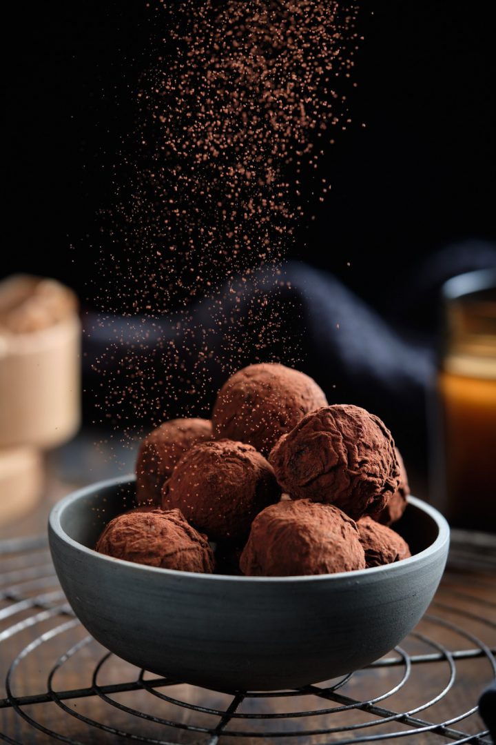 Vegan chocolate truffles being dusted with cocoa powder
