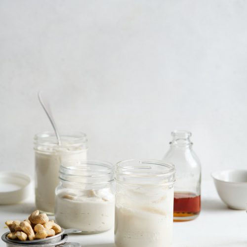 Different sized jars with vegan nut yogurt, cashews and maple syrup