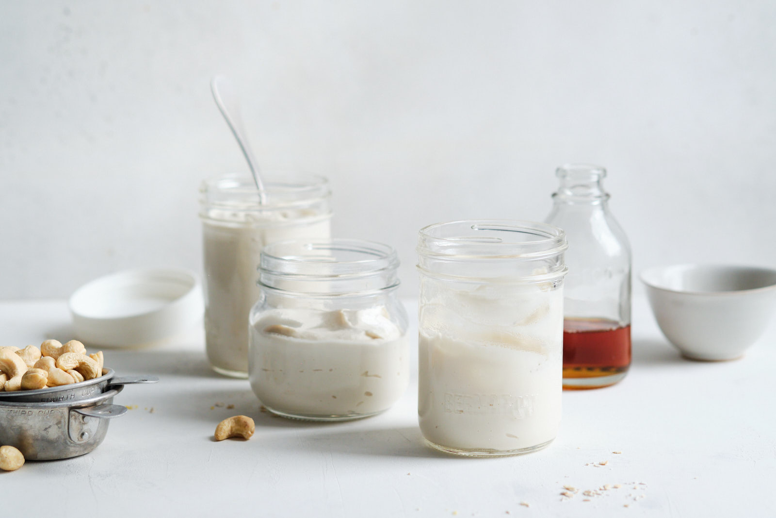 Different sized jars with vegan nut yogurt, cashews and maple syrup