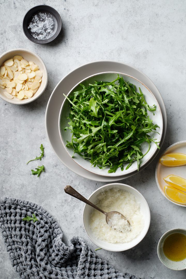 Ingredients for arugula pesto: sliced almonds, baby arugula, grated cheese