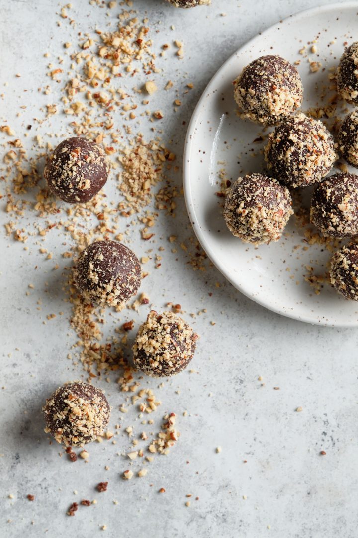 Easiest chocolate energy bites, rolled in finely chopped nuts, some sitting on a plate