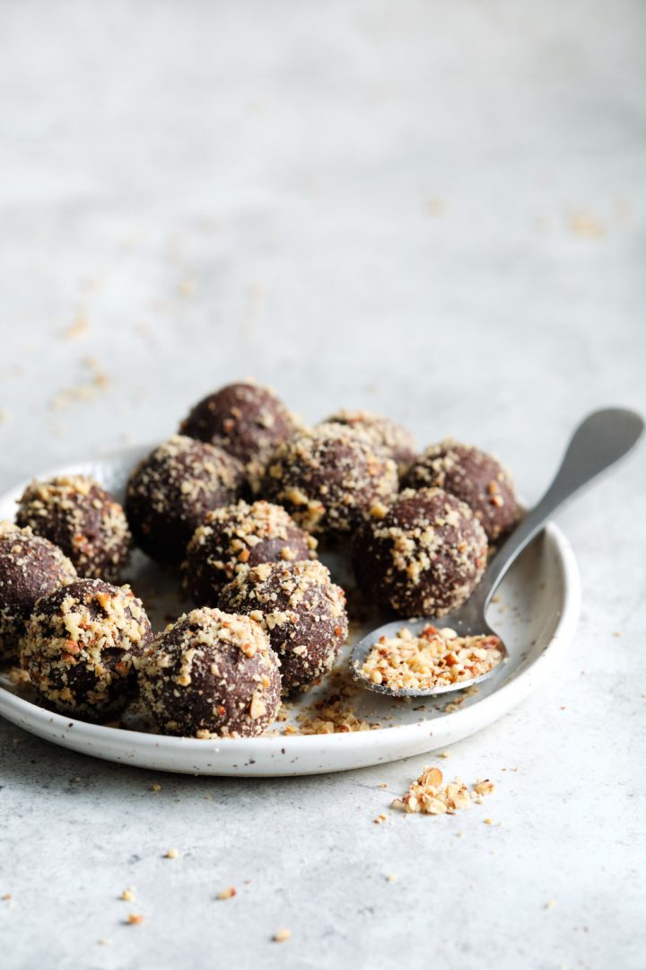 Easiest chocolate energy bites, rolled in finely chopped nuts, sitting on a plate