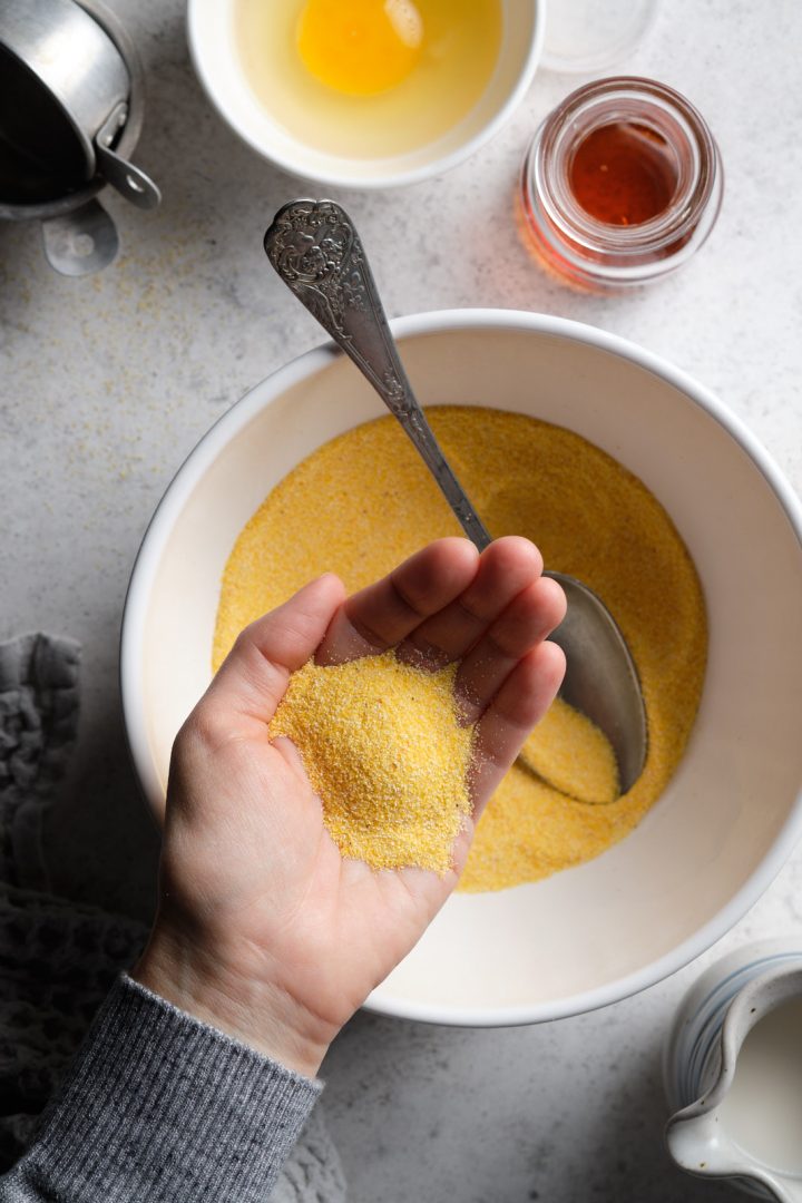 Cornmeal used to make gluten free cornmeal pancakes, shown in cook's hand