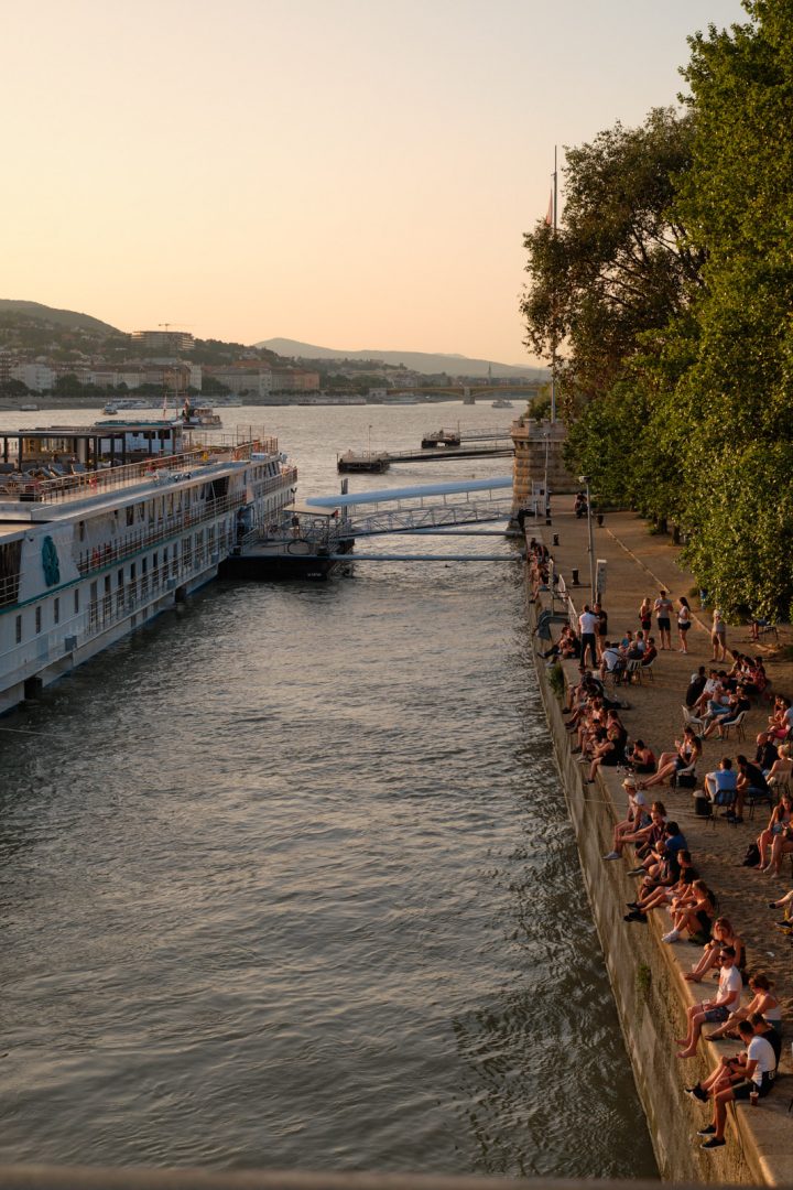 People watching the sunset on the shore of the Danube river